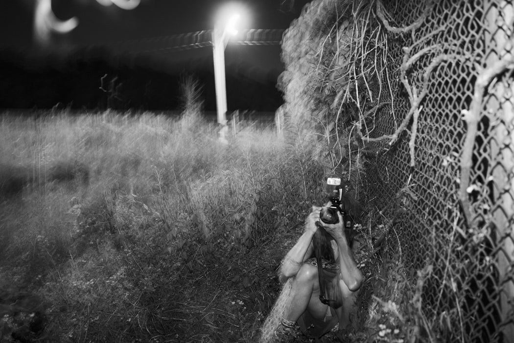 She Takes A Picture Crouched By The Fence