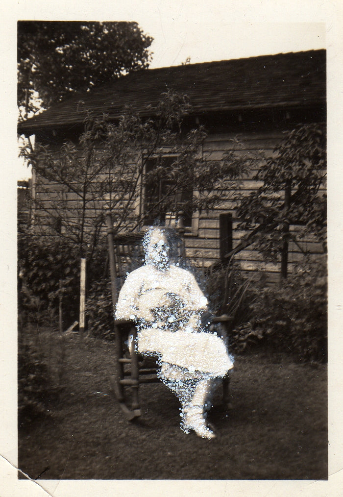Serious woman in white holding cat and seated in yard