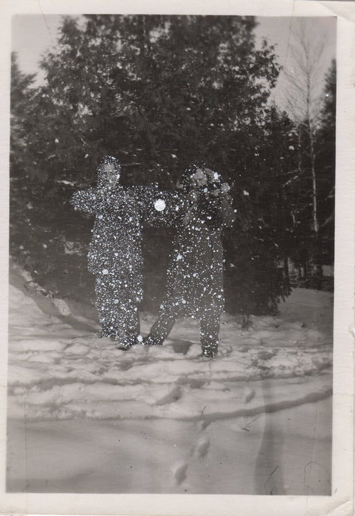 Two men posing with rifles in a snowy field