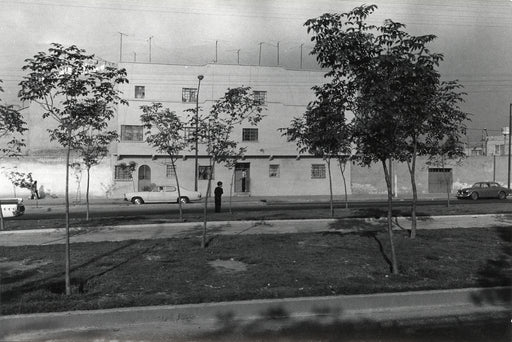 Untitled, Mexico [view of street with two cars passing and person standing in middle of view]