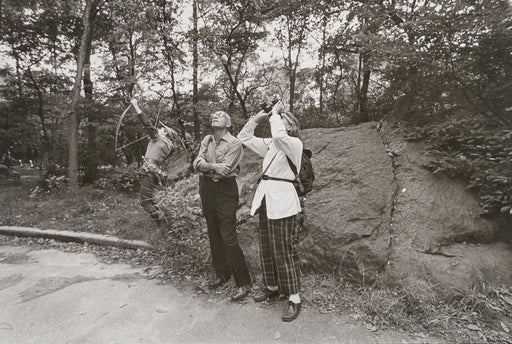 Untitled [Couple birdwatching with kid aiming a bow and arrow behind them]