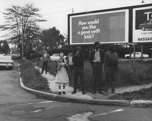Untitled [Spectators on street corner in front of billboard]